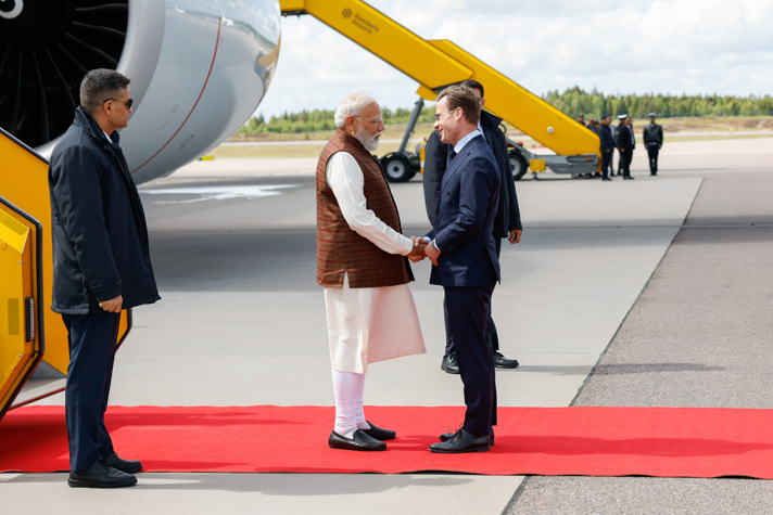 Ulf Kristersson skakar hand med Narenda Modi. Bakom dem syns en flygplansmotor.