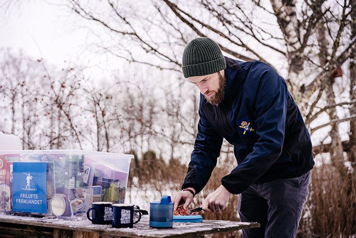 Minister för civilt försvar Carl-Oskar Bohlin står utomhus under vintern och förbereder mat ifrån en krislåda. 