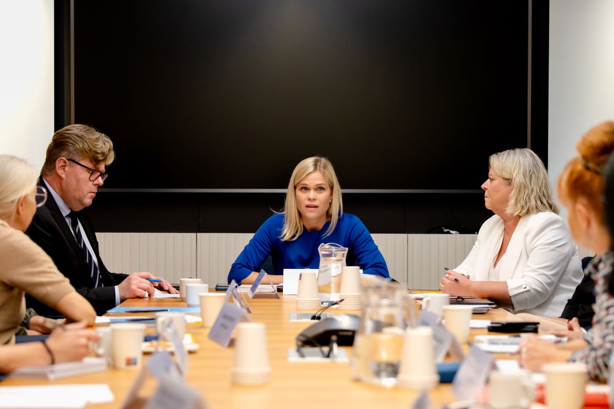 Jämställdhets- och arbetslivsminister Paulina Brandberg, justitieminister Gunnar Strömmer och socialtjänstminister Camilla Waltersson Grönvall sitter runt ett bord och samtalar med representanter för civilsamhällesorganisationer och myndigheter.