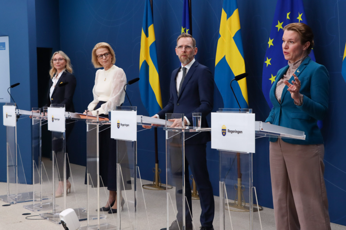 Fyra personer håller pressträff. De står bakom var sin talarstol.