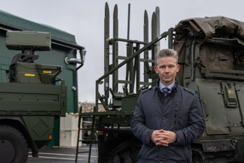 Man står framför ett luftvärnssystem och tittar mot kameran.