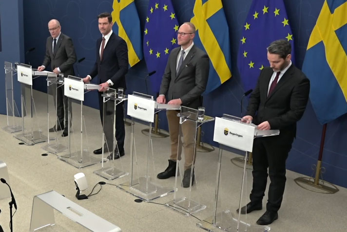 De fyra medverkande avbildade snett framifrån stående bakom var sin talarstol