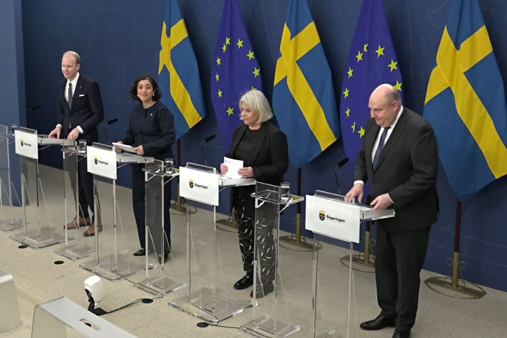 Fyra personer avbildade snett uppifrån bakom var sin talarstol