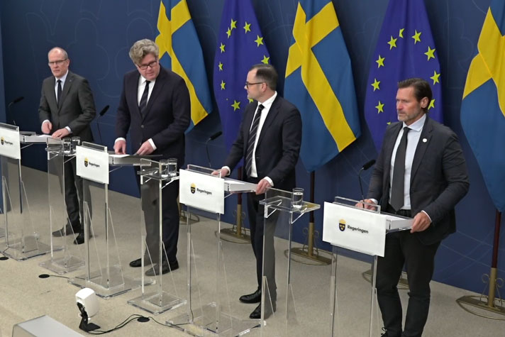 Fyra personer står sedda snett uppifrån står vid var sin talarstol