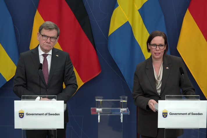 De två medverkande avbildade framifrån i halvfigur bakom var sin talarstol.