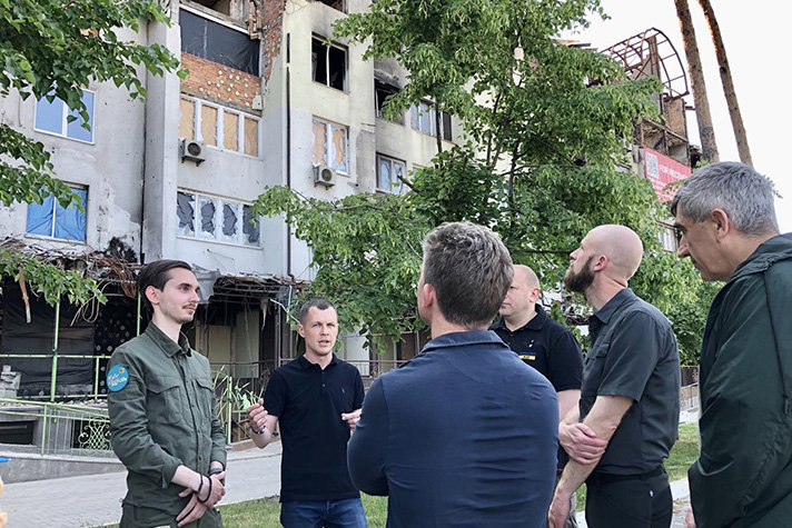 Försvarsminister Pål Jonson och minister för civilt försvar Carl-Oskar Bohlin tittar upp mot ett svårt skadat bostadshus i Irpin.