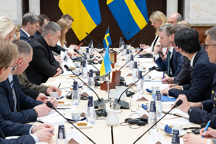 Mykhail Fedorov och Pål Jonson sitter på varsin sida av långsidan av ett långbord. Runt bordet sitter personer ur bägge delegationerna.