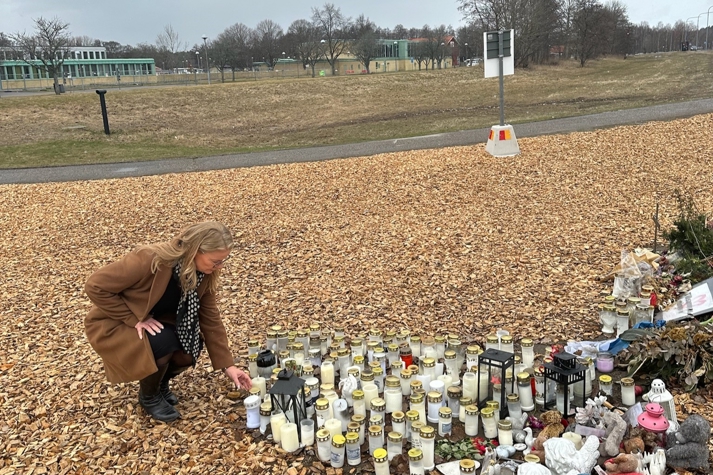 Skolministern ställer ner ett ljus vid minnesplatsen för våldsdådet på Campus Risbergska.
