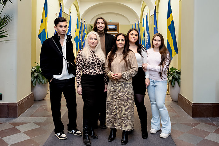 Gruppbild med kulturministern i mitten och rådet runt henne. I bakgrunden syns en korridor med flaggor.