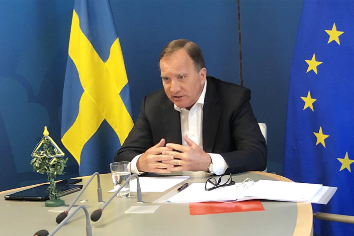 Stefan Löfven sitter vid bord och deltar i videomöte
