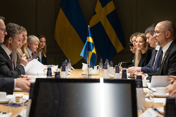 Representanter från Sverige och en delegation från Ukraina har ett möte. I bakgrunden skymtar Sveriges och Ukrainas respektive flagga.