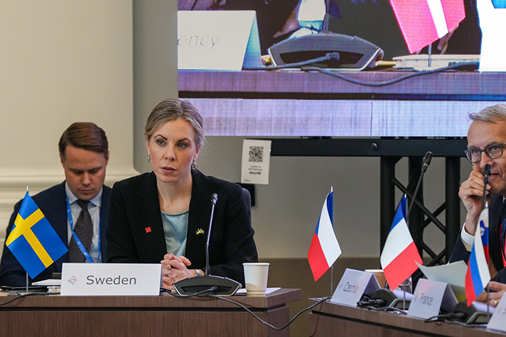 Jessica Rosencrantz sitter i mötesrummet i Lviv. Framför henne en skylt med texten "Sweden".