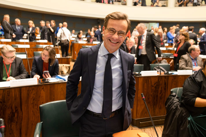 Statsminister Ulf Kristersson stående vid sin plats i bänkraderna - Nordiska rådet Helsingfors