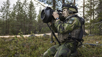 Pansarvärnrobot 57 på väg att avfyras av en svensk soldat sittandes på knä i skogsmiljö