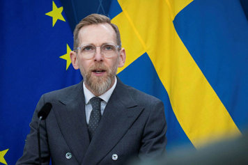 Socialminister Jakob Forssmed fotograferad framifrån i kvartsfigur med fanor i fonden.