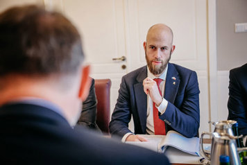 Carl-Oskar Bohlin sitter vi ett bord, andra mötesdeltagare skymtar.