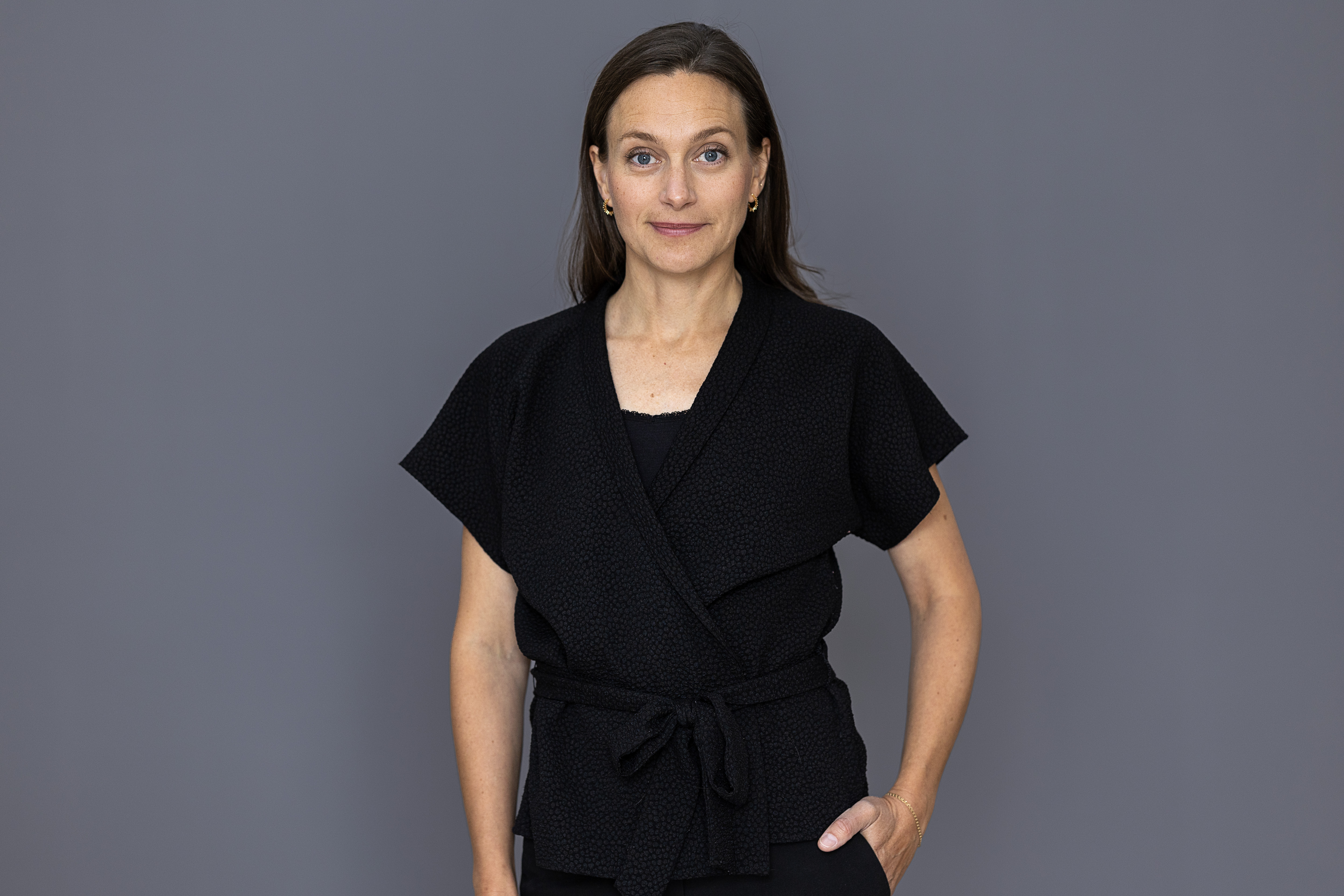 Porträttbild av statssekreterare Ulrika Hoff framför en grå bakgrund.