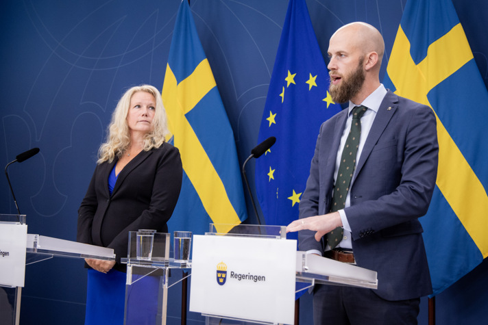 Carl-Oskar Bohlin och Pia Clerté står och talar vid varsin talarstol i regeringens pressrum.