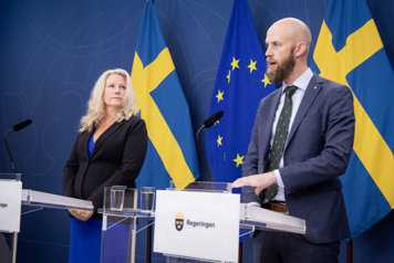Carl-Oskar Bohlin och Pia Clerté står och talar vid varsin talarstol i regeringens pressrum.