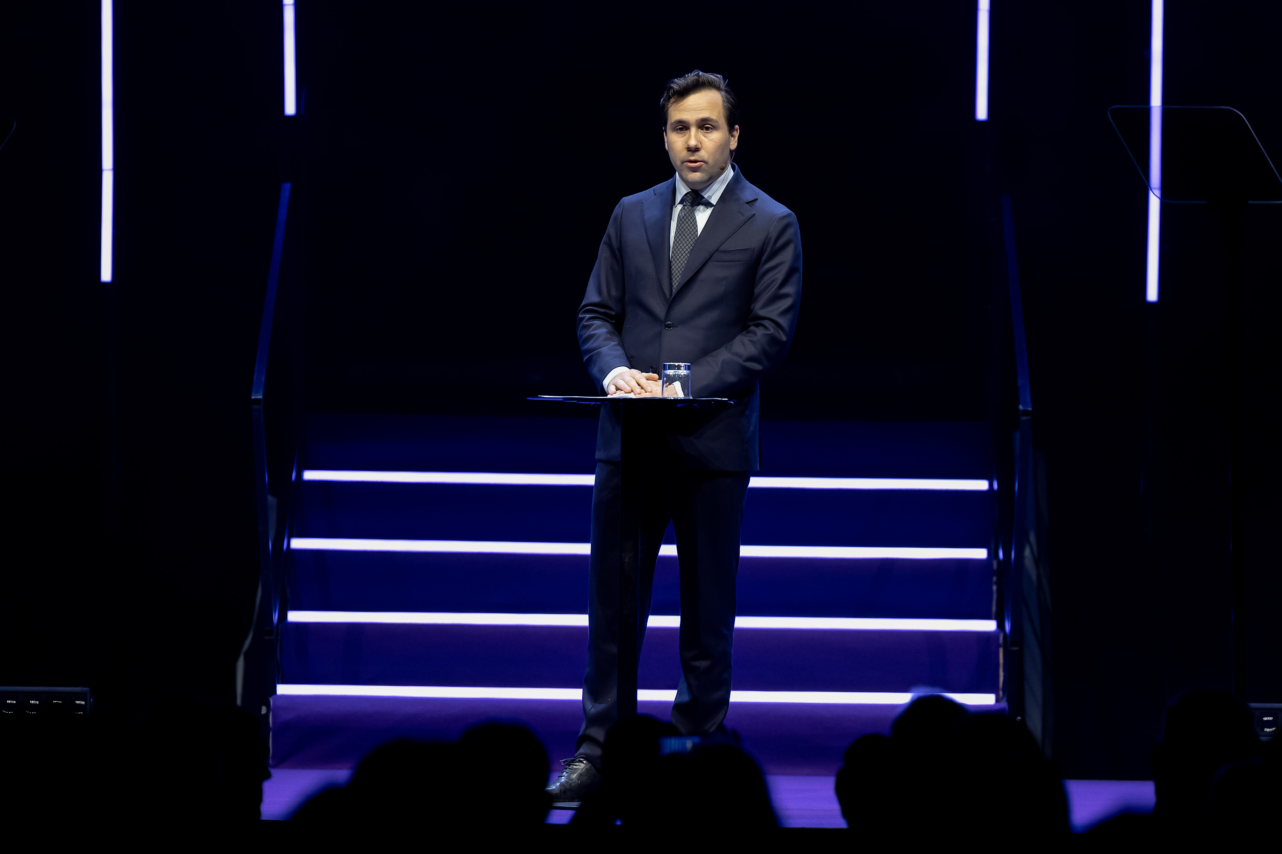 Bistånds- och utrikeshandels­minister Benjamin Dousa står på e scen och talar.. 