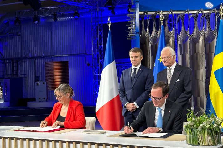 Utbildningsminister Mats Persson och Frankrikes minister för högre utbildning och forskning Sylvie Retailleau undertecknar avsiktsförklaringen på Alfa Laval i Lund. Bakom dem står Frankrikes president Emmanuel Macron och H.M. Konungen.