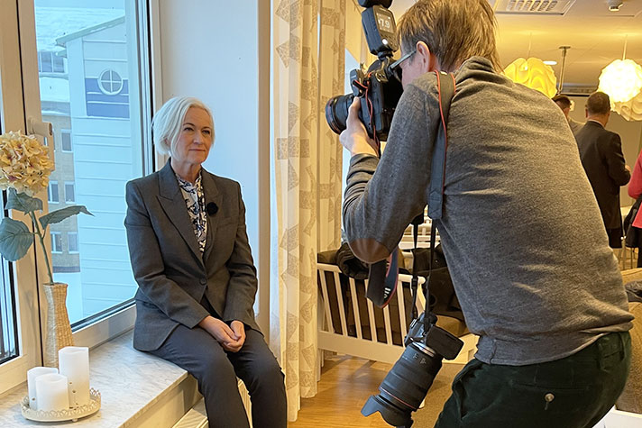 En fotograf lutar sig fram och tar ett porträtt av en kvinna.