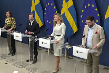 De medverkande står bakom var sin talarstol fotograferade i helfigur snett framifrån.