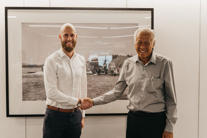 Carl-Oskar och Ng Eng Hen skakar hand och ler in i kameran.