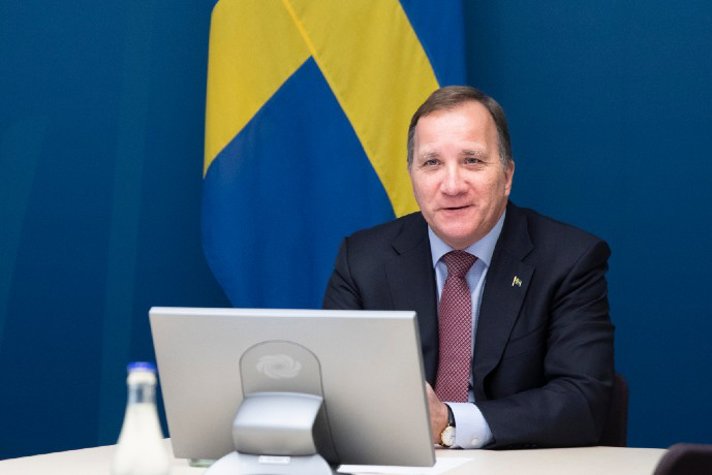 Statsminister Stefan Löfven sitter och pratar framför en skärm under ett videomöte.
