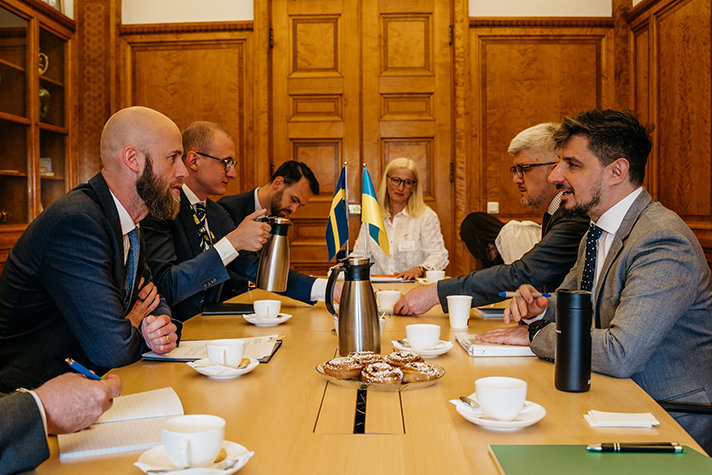 Till vänster i bild minister för civilt försvar Carl-Oskar Bohlin och biträdande minister för veteranfrågor i Ukraina Oleg Shymanskyi. Flera personer sitter med dem runt ett bord inomhus.