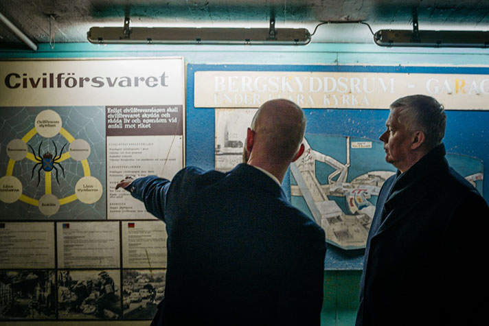 Två personer står inomhus i ett rum. 