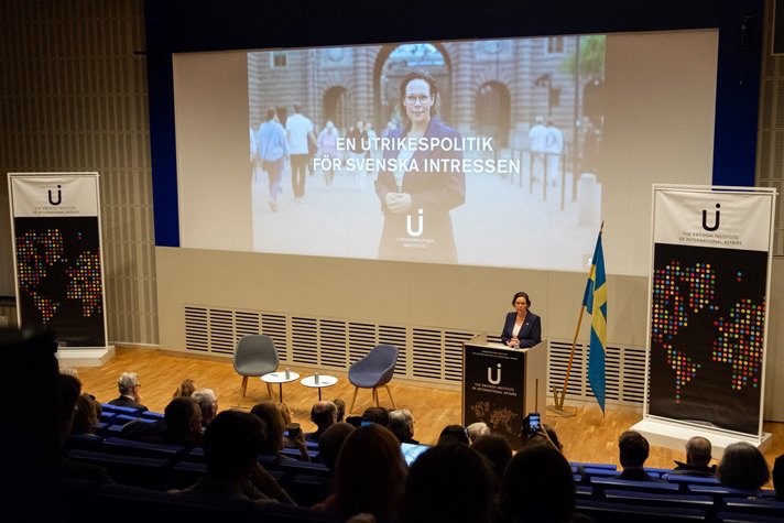 Utrikesminister Maria Malmer Stenergard i en talarstol med publik framför.