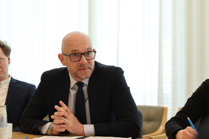 Arbetsmarknadsminister Johan Britz sitter vid ett bord och talar inför arbetsmarknadspolitiska rådet