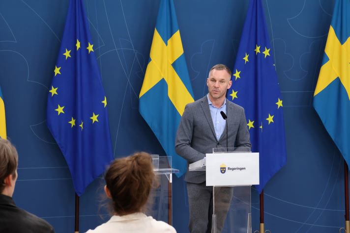 Erik Slottner står på en scen och svarar på journalisters frågor.