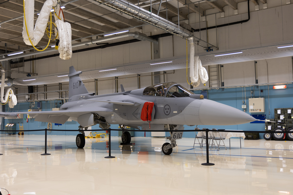 Gripen E står uppställd i en ljus hangar