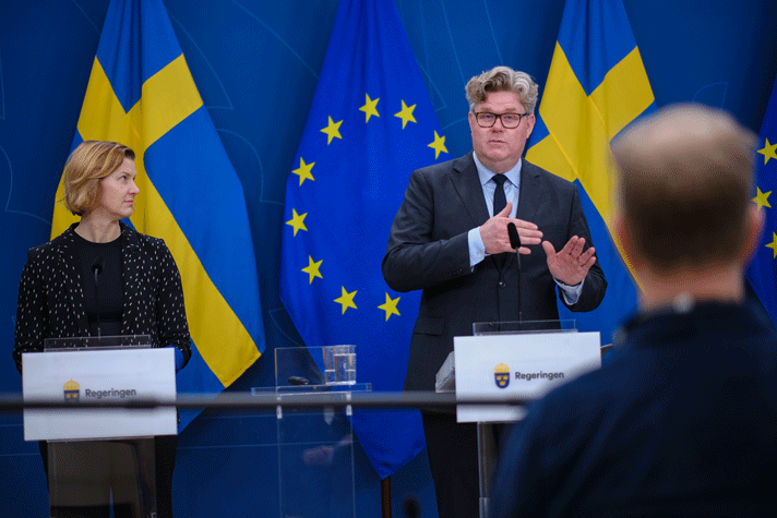 Nina Larsson och Gunnar Strömmer står vid varsin talarstol i pressrummet på Rosenbad. I bakgrunden syns svenska och EU-flaggan.