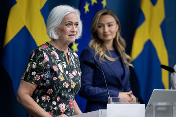 Porträtt av Acko Ankarberg Johansson och Ebba Busch på en presskonferens. Bakom dem finns svenska flaggor och EU-flaggor.