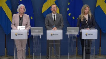 Tre personer står bakom varsin talarstol. Bakom dem blå bakgrund med EU- och svenska flaggor.