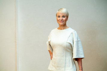 Äldre- och socialförsäkringsminister Anna Tenje i vit klänning vänd mot kameran.