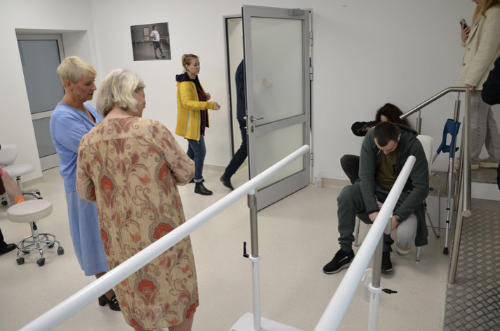 Anna Tenje och Camilla Waltersson Grönvall ser på när en man ska göra rehabiliteringsövnningar.