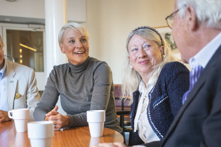 Anna Tenje skrattar och fikar med pensionärer. 