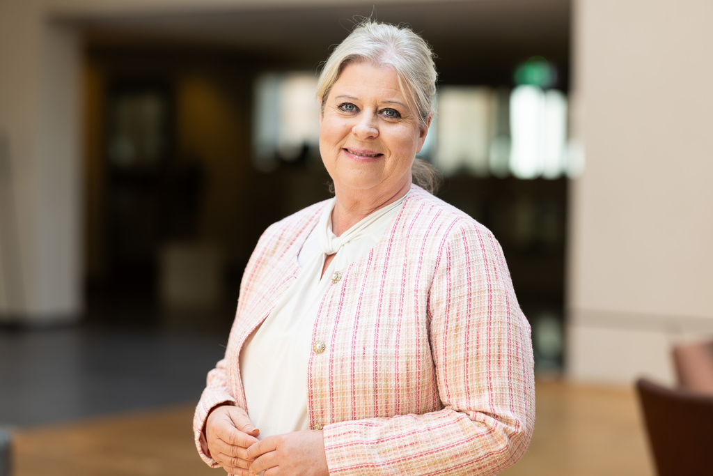 Socialtjänstministern i ljusrosa kavaj, ler mot kameran. 