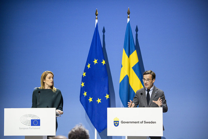 Roberta Metsola och Ulf Kristersson står framför varsin talarstol. I bakgrunden syns EU- och svenska flaggan.