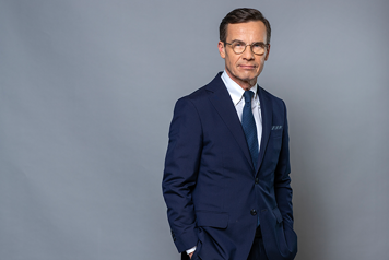 Ulf Kristersson i halvfigur mot grå bakgrund.