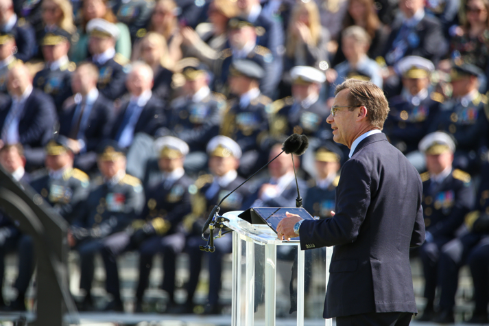 Statsministern står vid ett podium framför publik.