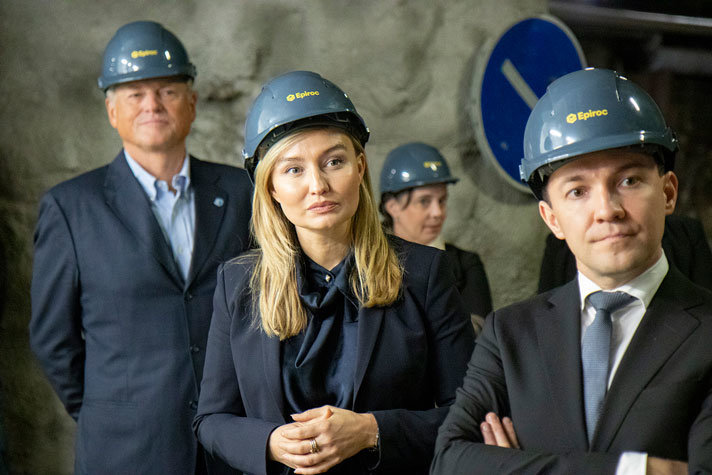 Ebba Busch står tillsammans med Finlands näringsminister i en gruva. De har skyddshjälmar på sig och i bakgrunden syns två andra personer med hjälm och en grå bergsvägg.