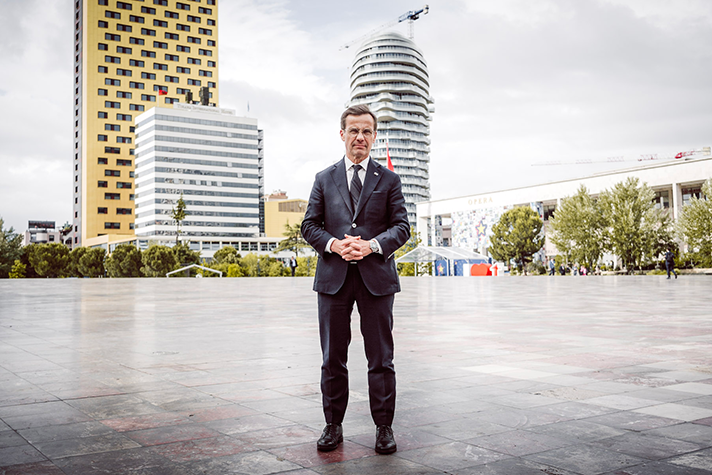 Helkroppsbild på Ulf Kristersson som står på ett tomt torg i Tirana.
