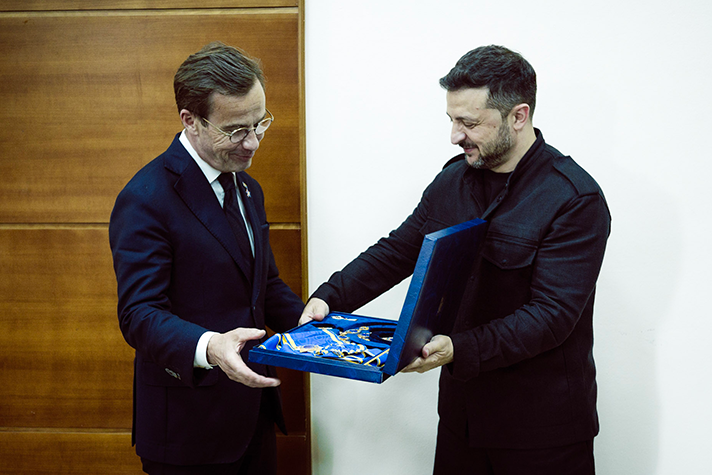 Volodymyr Zelenskyj räcker över ett etui med en ordensmedalj till Ulf Kristersson. Bilden är tagen inomhus.