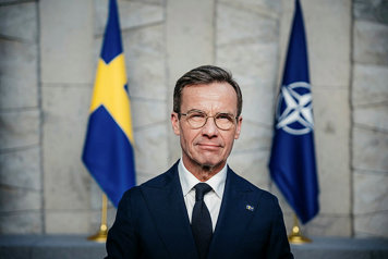 Kristersson står framför svenska flaggan och Natoflaggan