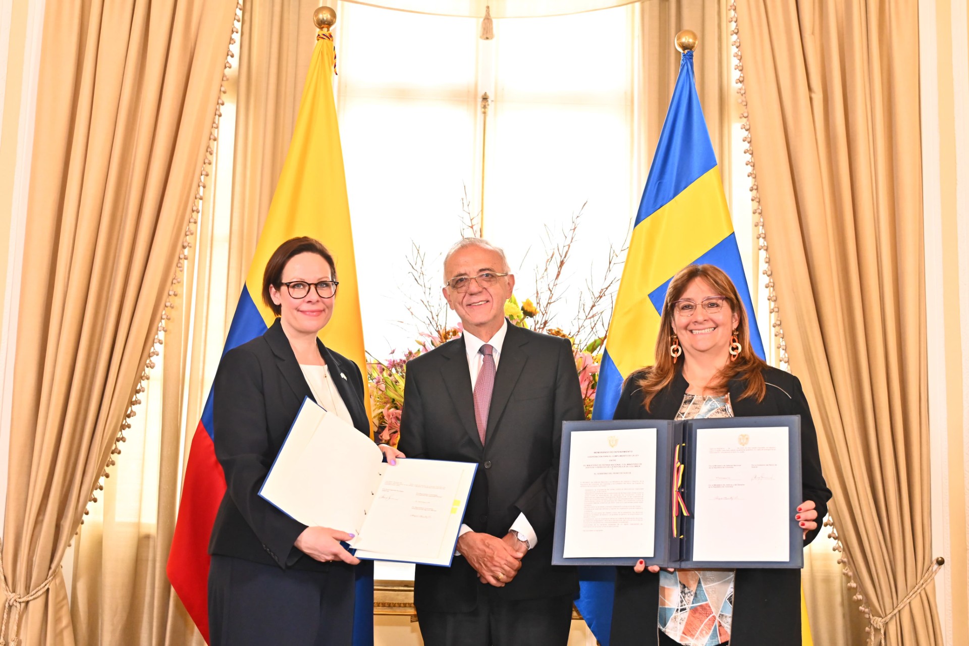 Utrikesminister Maria Malmer Stenergard, Colombias försvarsminister Iván Velásquez och justitieminister Ángela María håller upp ett bilateralt avtal om brottsbekämpning. 